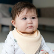 Baby wearing a pale yellow Ziggle bandana bib.
