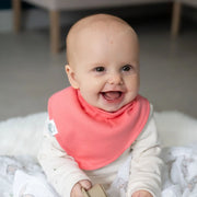 Baby girl wearing a coral pink Ziggle bandana bib.