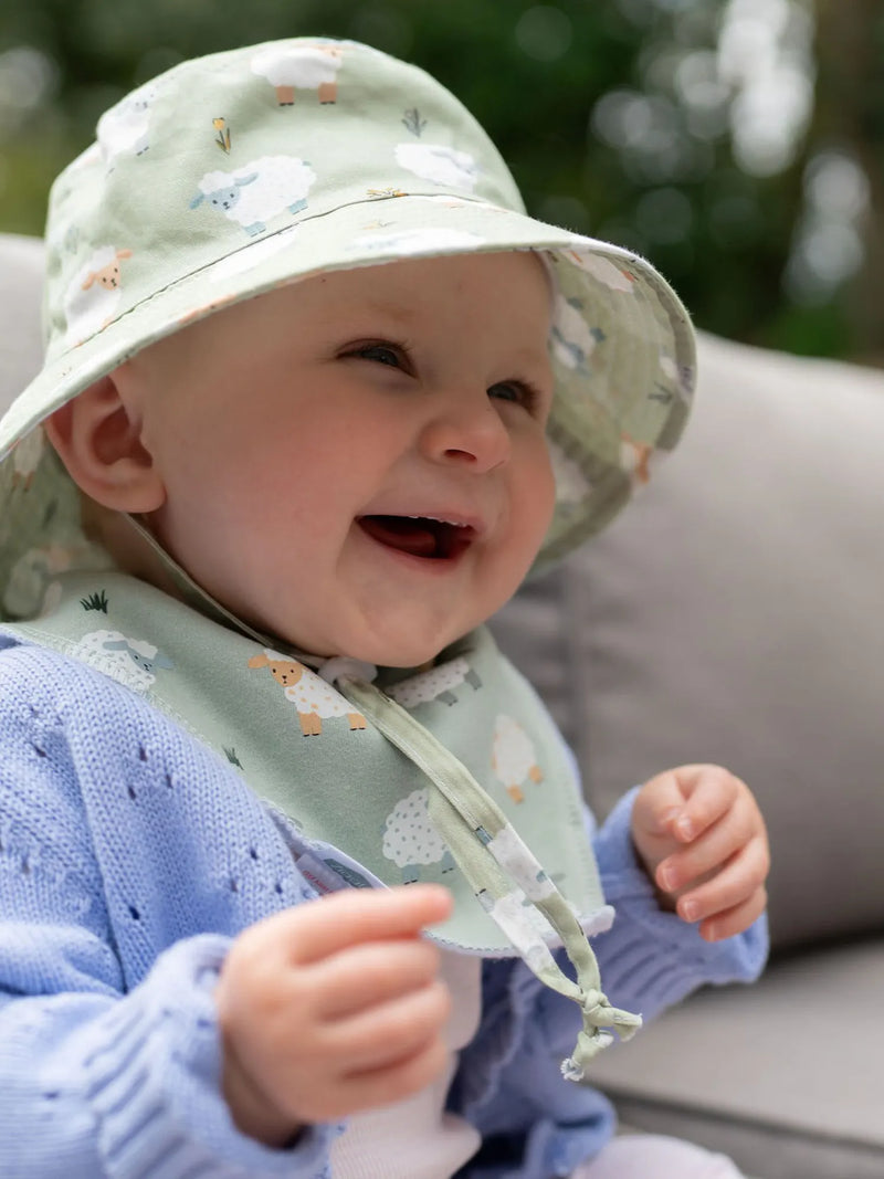Smiling baby wearing the ziggle sheep sun hat.