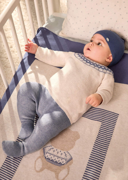 Baby boy in a cot wearing the Mayoral knitted leg warmer set.