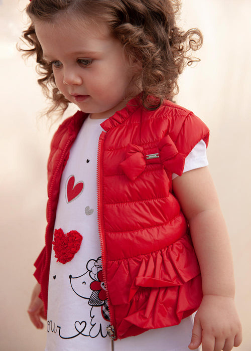 Baby girl wearing a bright red padded gilet.